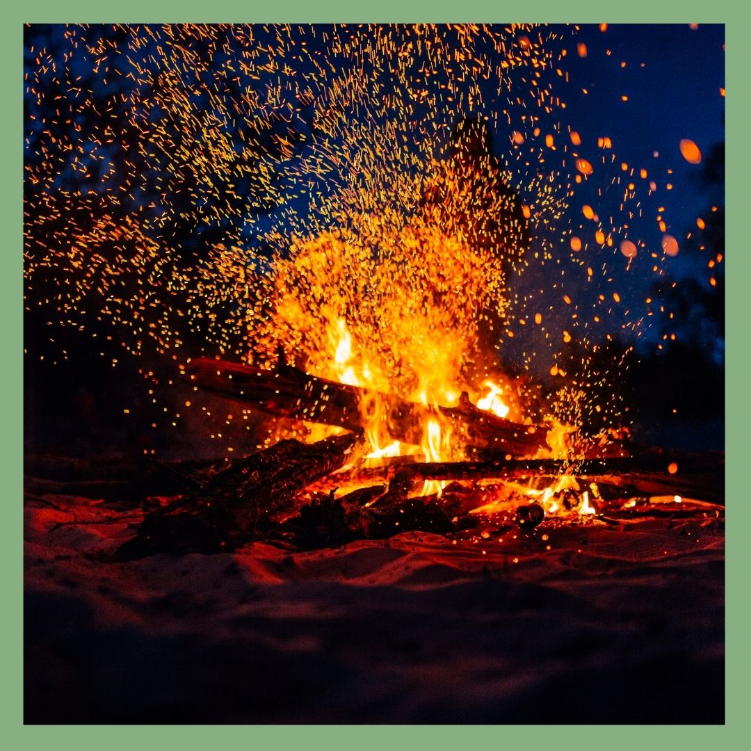 Campfire with sparks flying in dark surroundings.