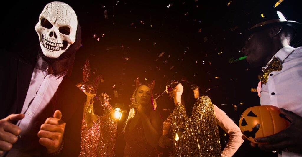 Group in Halloween costumes celebrating with confetti and decorations.