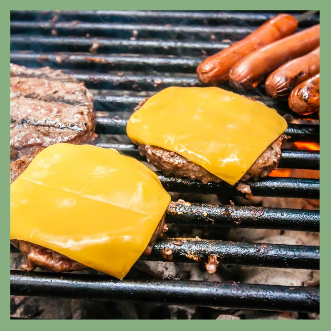 Cheeseburgers and hot dogs grilling on barbecue.
